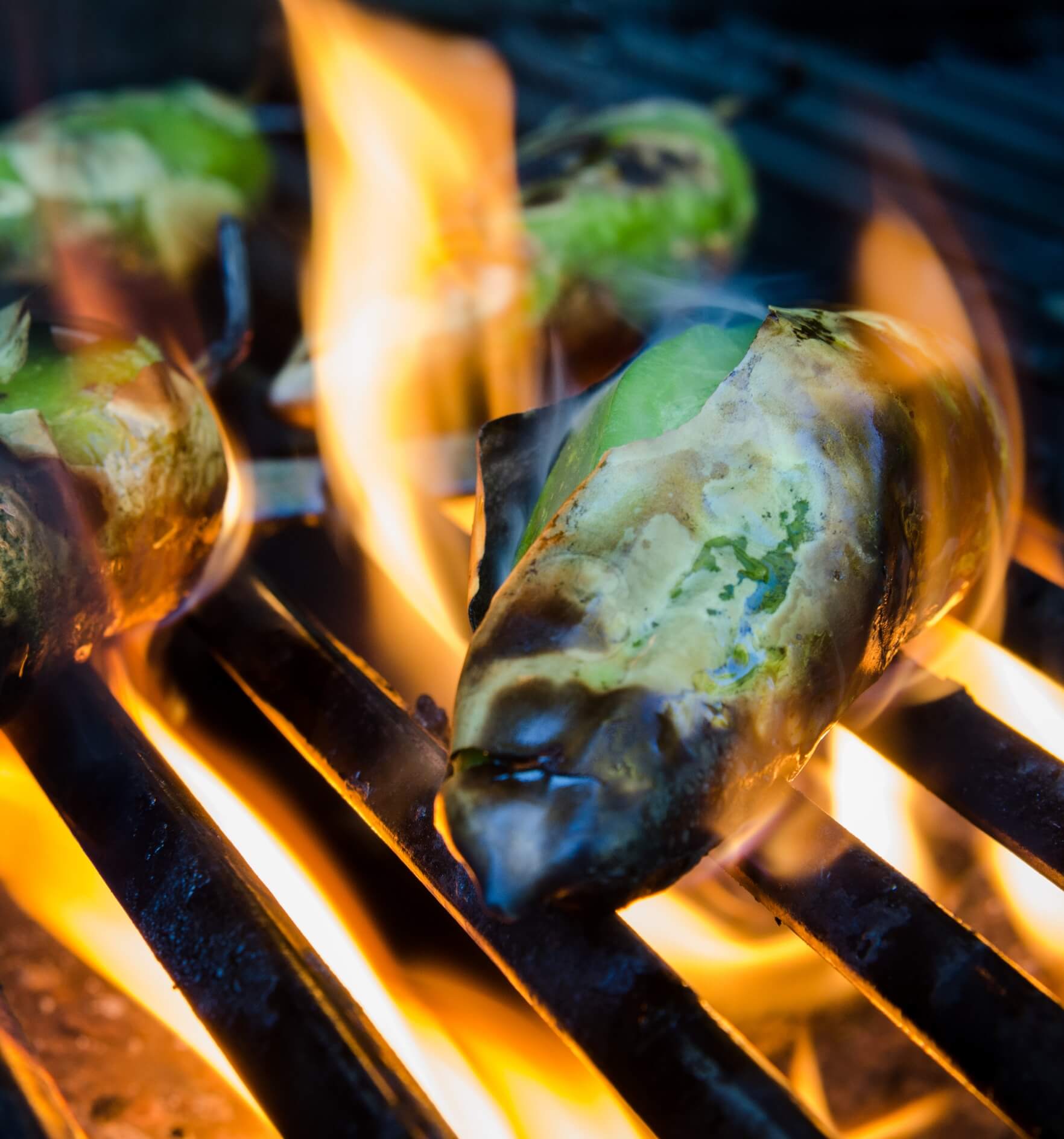 Image showing small green peppers roasted on flames on a grill